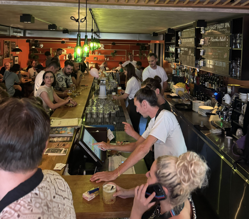 Die Bierstube des Roten Kater am Abend — volle Theke, Team am Zapfen